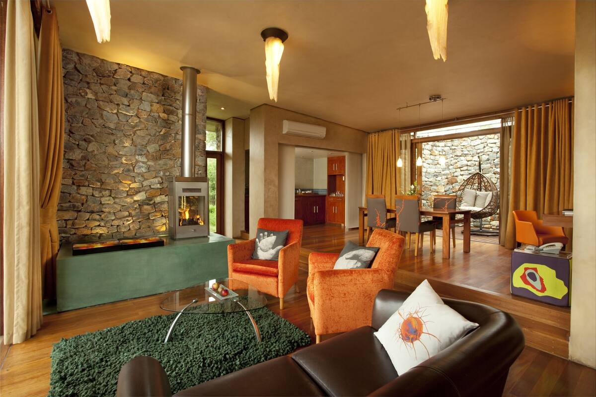 Una sala de estar moderna con pared de piedra, sofás de cuero y chimenea.