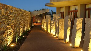 A stone-walled corridor with illuminated columns and a pathway leading to a building. - Forum Homini Boutique Hotel (Krugersdorp)