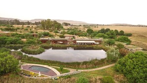 A hotel with a swimming pool, outdoor seating, and a view of the surrounding landscape. - Forum Homini Boutique Hotel (Krugersdorp)