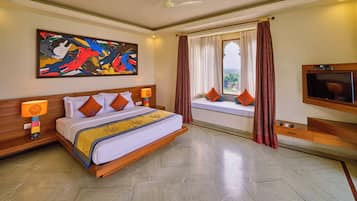 A hotel room with a bed, a television, a window with curtains, and a painting on the wall.