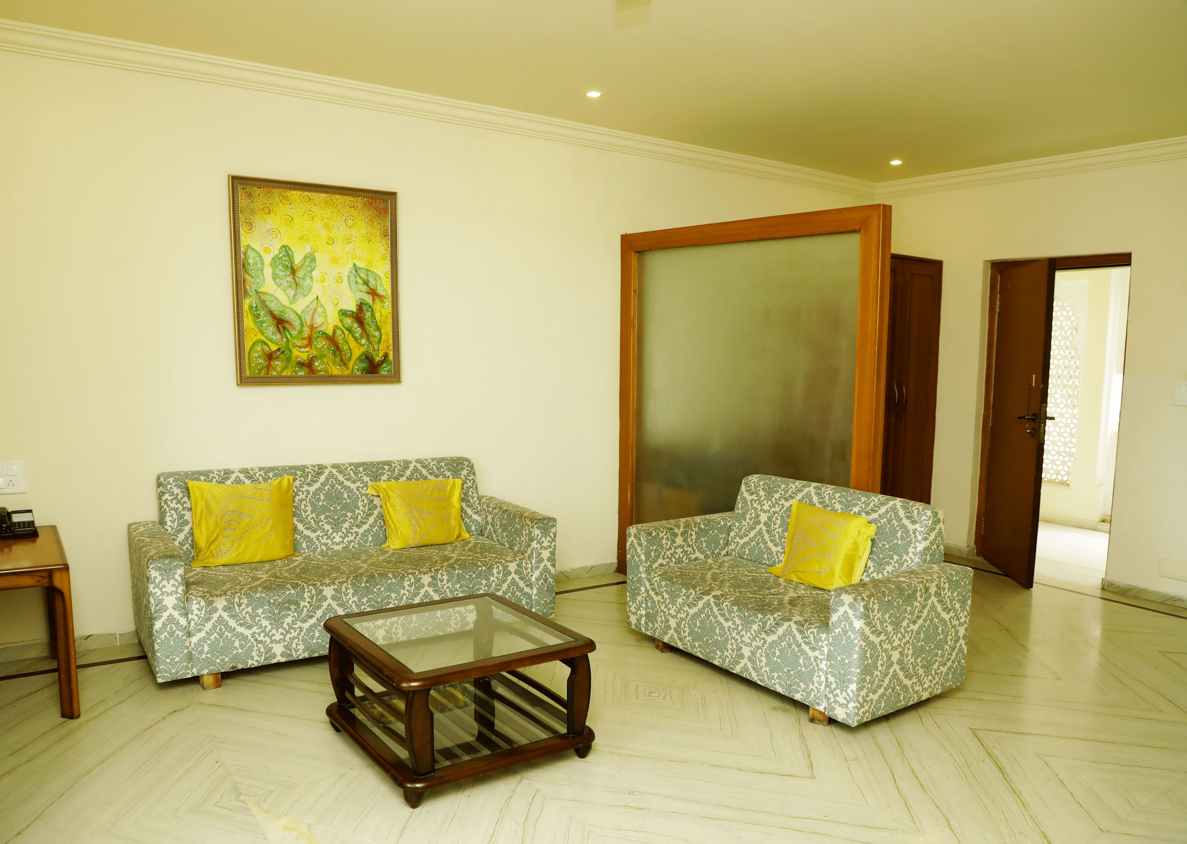 A living room with two patterned sofas, a glass coffee table, and a large mirror.