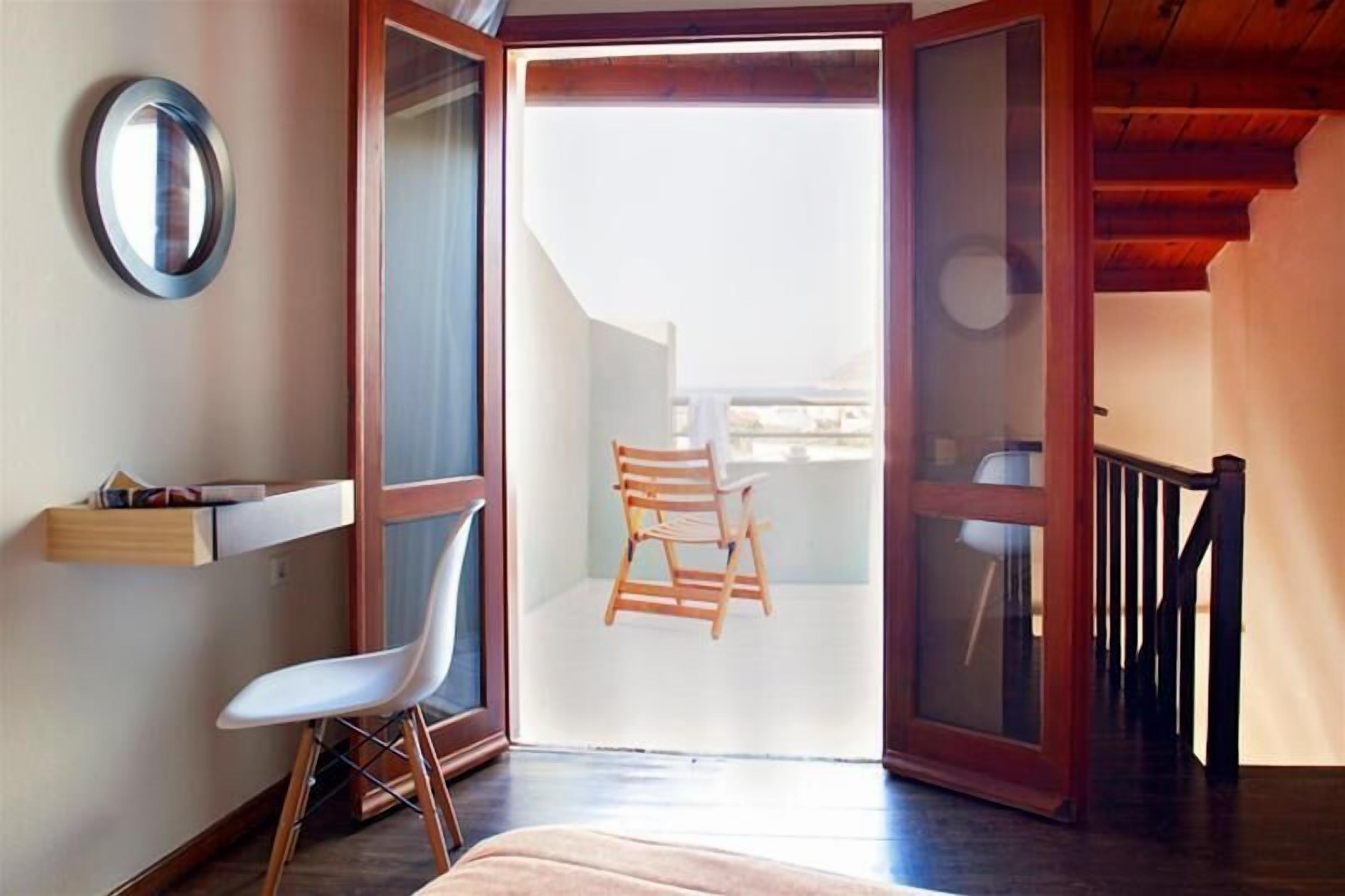 A room with a wooden chair, a white chair, and a small table with books.