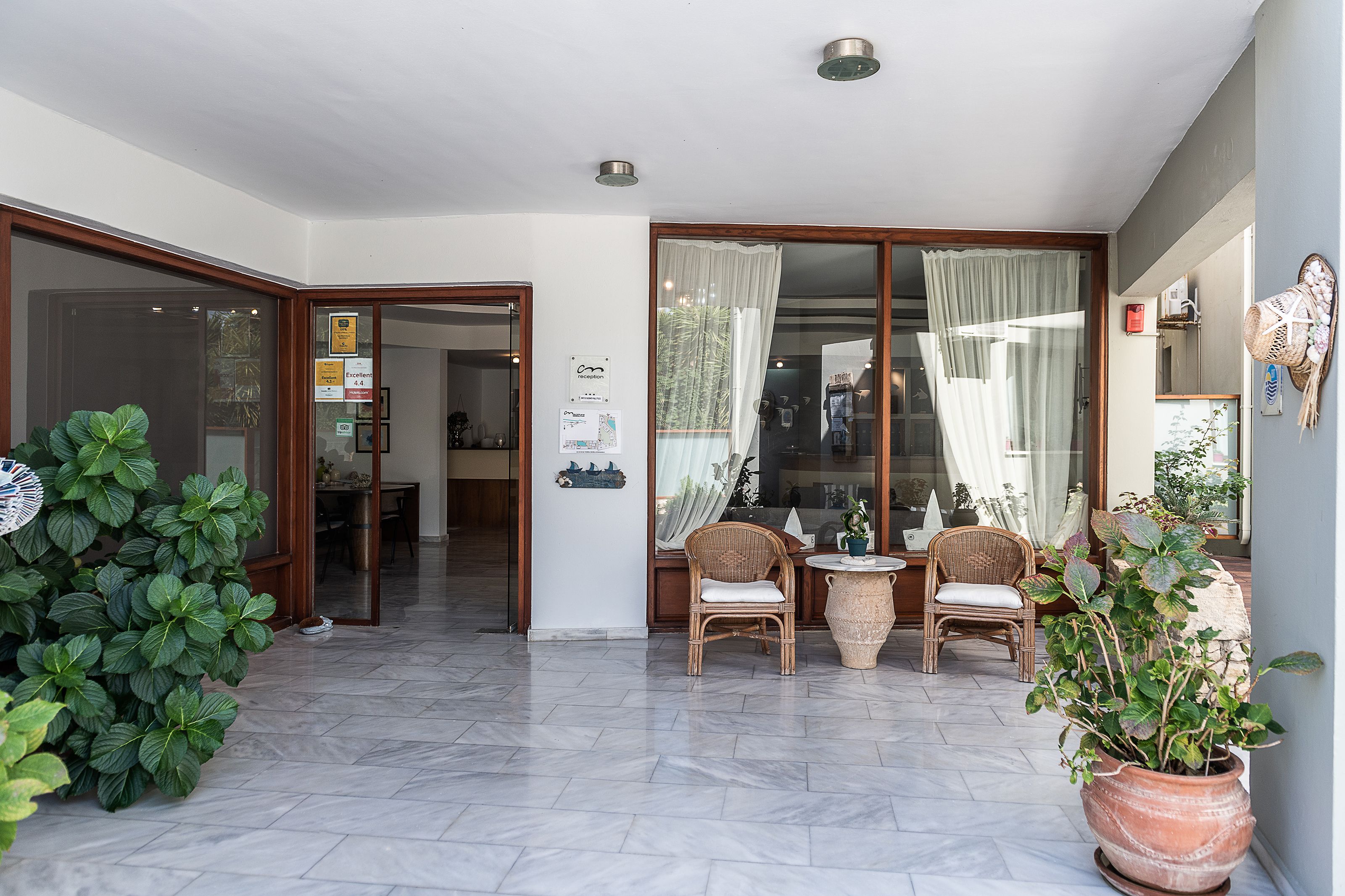 A spacious patio with a dining area, including wicker chairs and a table, and a large potted plant.