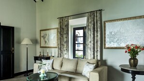 Un salon avec un canapé, une petite table sur laquelle est posé un vase de fleurs, une lampe et un tableau encadré au mur.