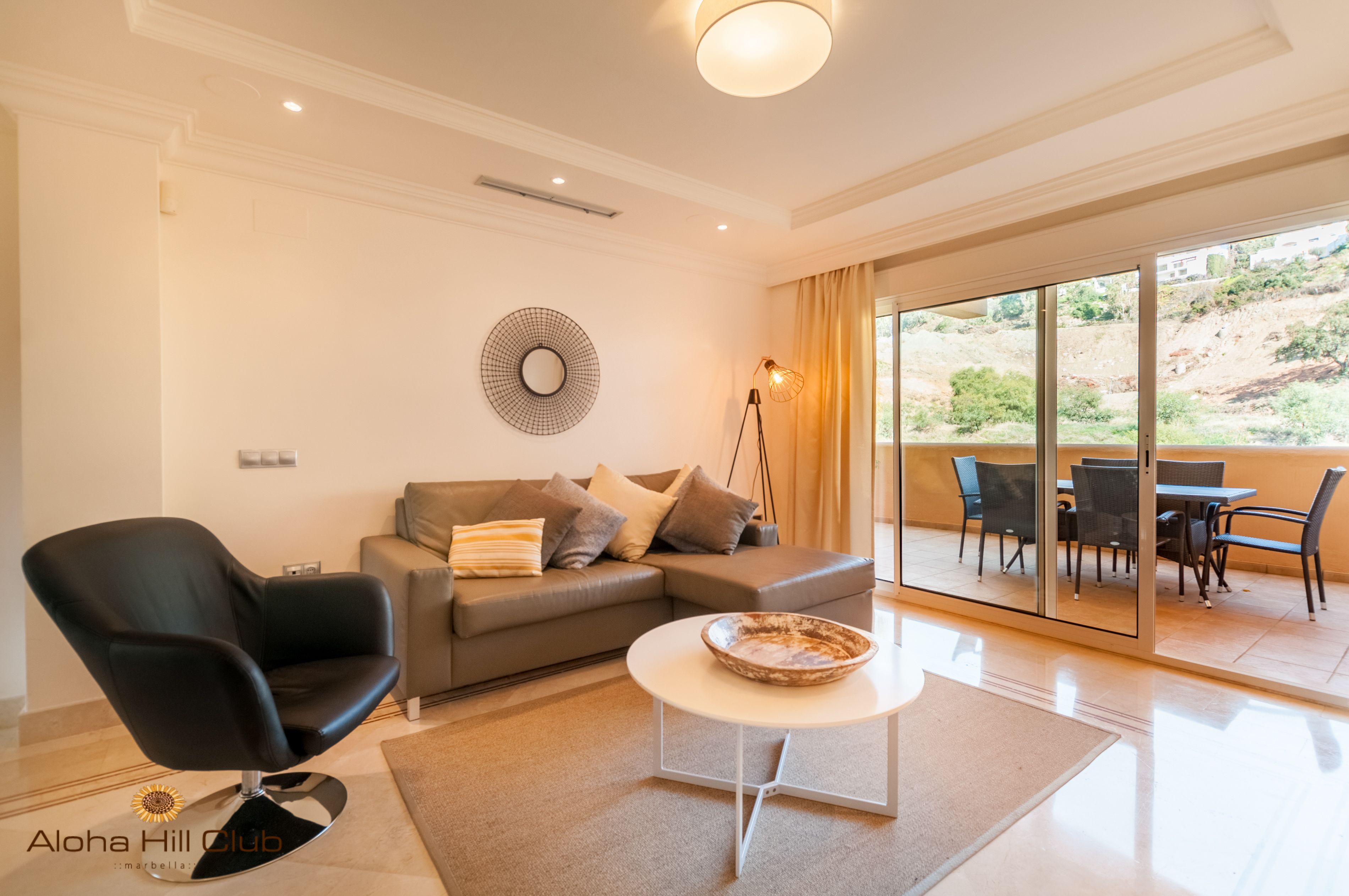 Un salon moderne comprenant un canapé, un fauteuil noir, une table basse et un coin repas avec des chaises et une table.