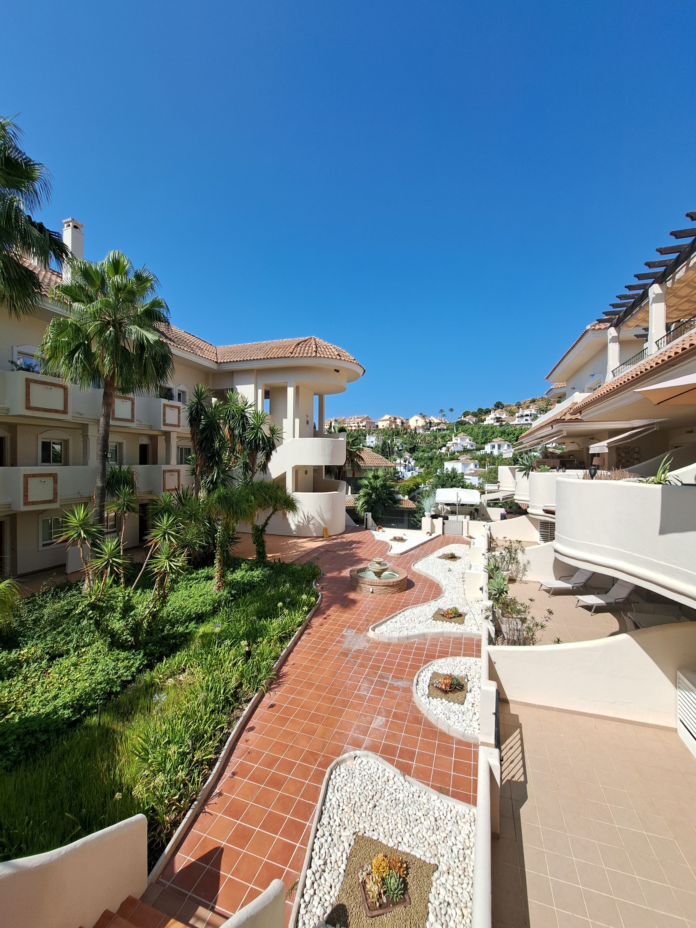 A resort with a central courtyard, palm trees, and terracotta-tiled walkways.