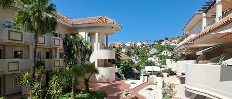 A resort with a central courtyard, palm trees, and terracotta-tiled walkways.