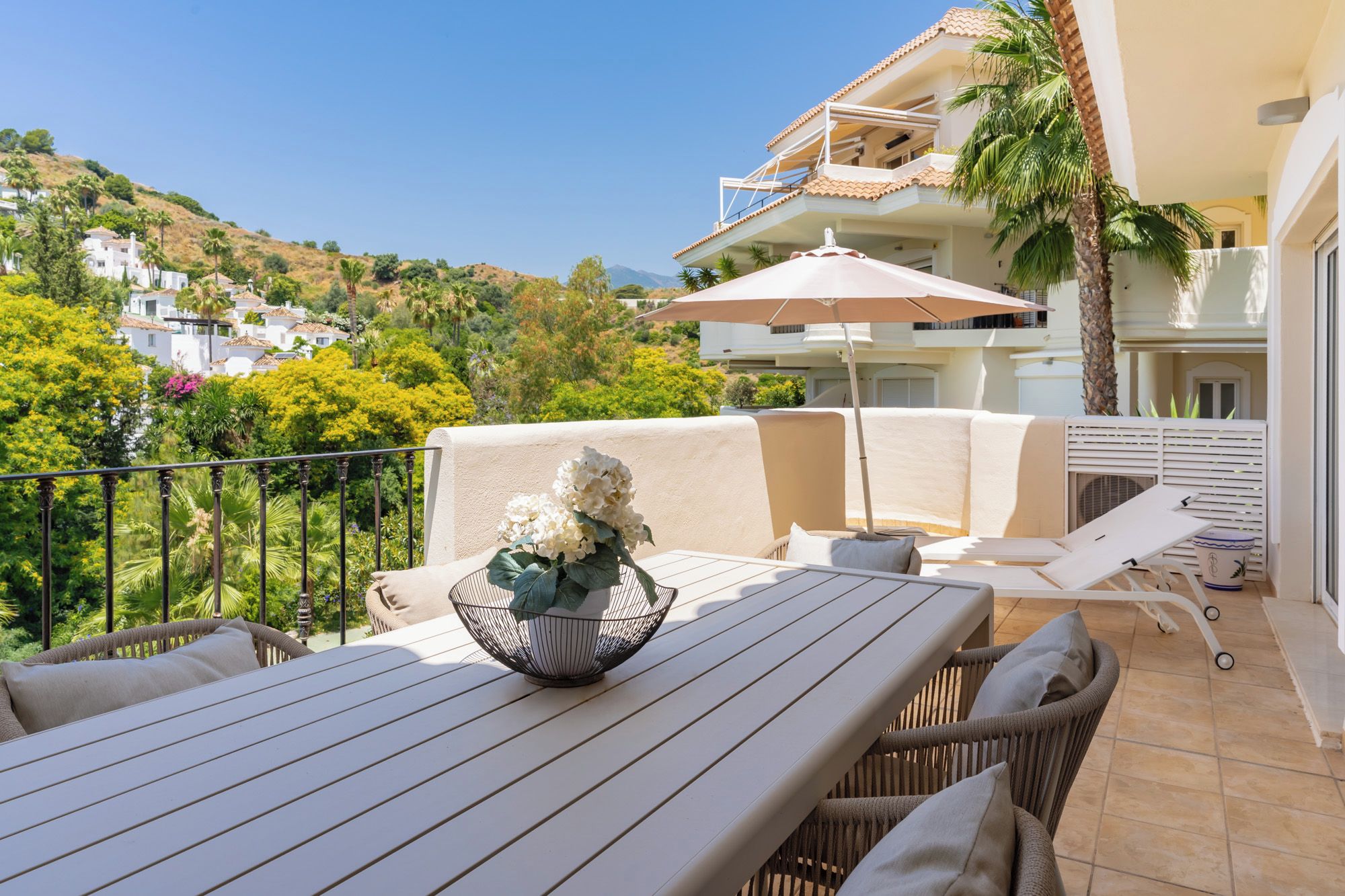 A balcony with a table, chairs, and a decorative bowl.