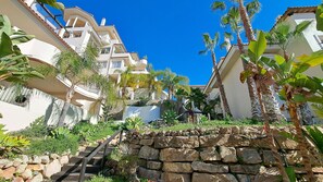 Zona residencial con edificios de varios pisos, una escalera de piedra y vegetación tropical.