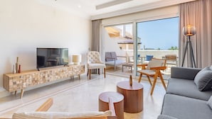 Un soggiorno moderno con una TV a schermo piatto, un tavolino consolle in legno, un divano e un balcone con mobili da esterno.