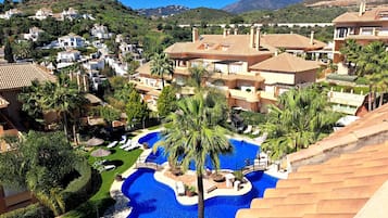 Un resort con piscina central, varias villas y montañas al fondo.