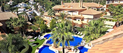 A resort with a central swimming pool, multiple villas, and a mountainous backdrop.