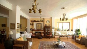 Un salon spacieux, meublé de meubles en osier, agrémenté d’un grand tapis et doté d’une cheminée.