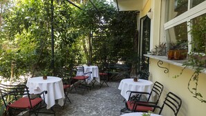 Un espace extérieur aménagé avec des tables et des chaises, entouré de verdure.