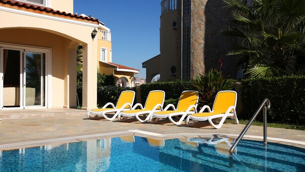 A swimming pool with yellow lounge chairs and a clear blue sky.