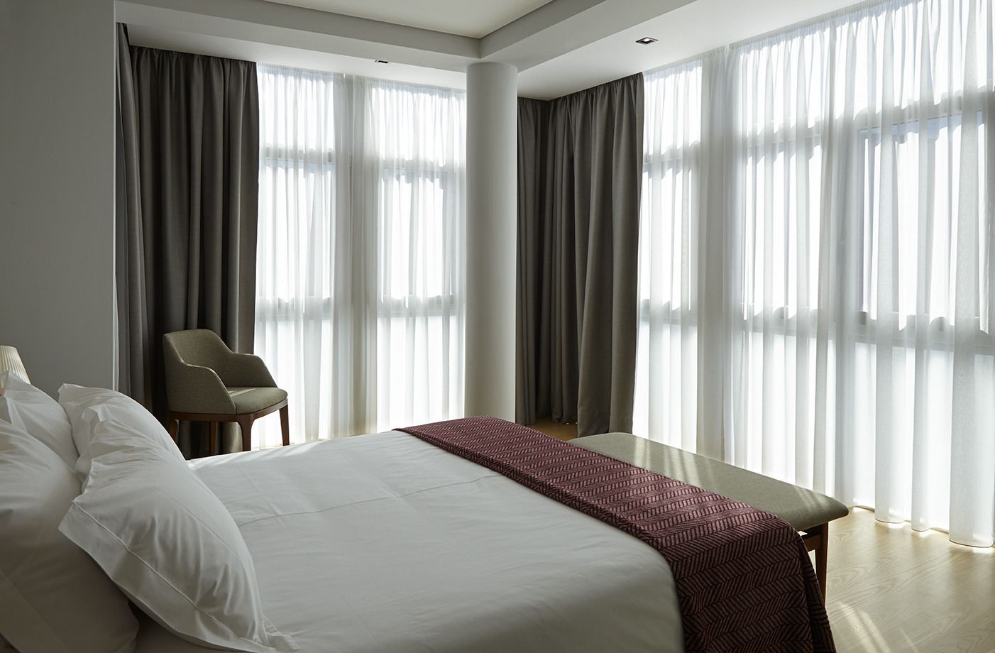 A modern hotel room with a large bed, a chair, and a desk.