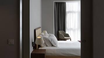 Una moderna camera d'albergo con un letto rifatto, una sedia, una lampada e un tappeto colorato.