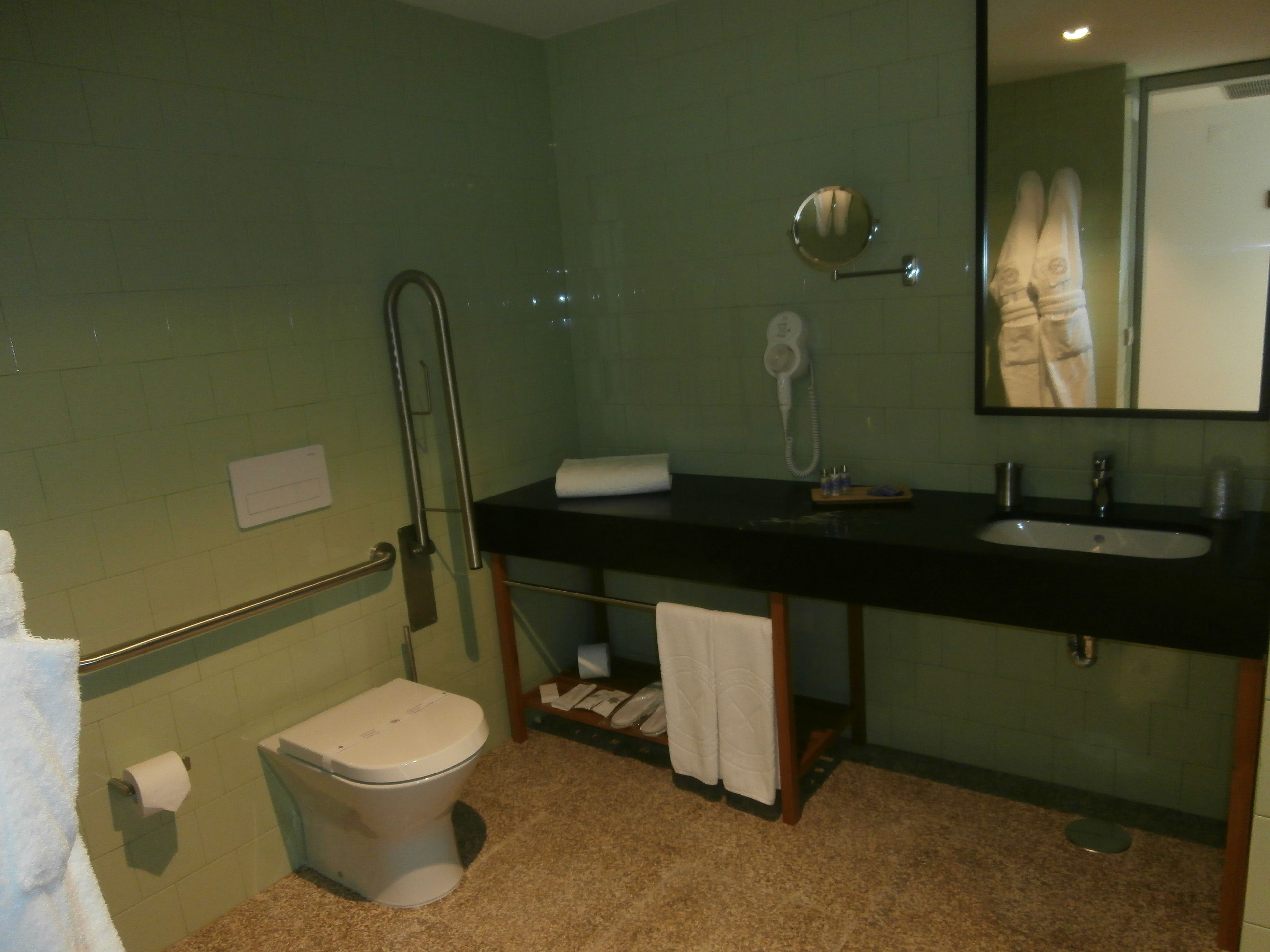 A bathroom with a toilet, sink, and mirror.