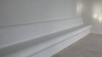 Un angolo di una stanza con un muro strutturato e un pavimento tappezzato.