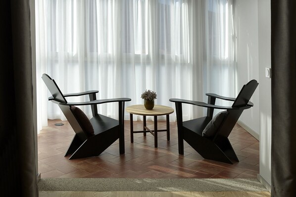 A room with two black chairs, a small round table, and a potted plant.