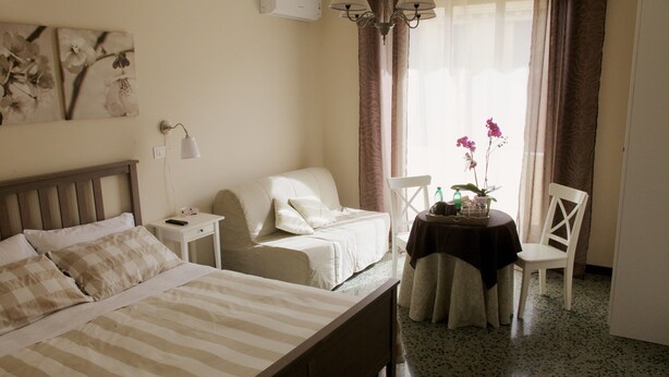 A bedroom with a bed, bedside tables, a small table with a chair, and a window with curtains. - La Casa In Prati (Rome)