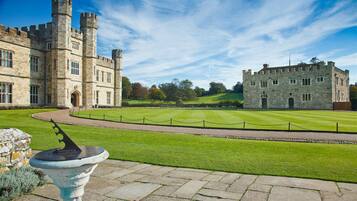 A historic stone castle with multiple towers and a well-maintained lawn.