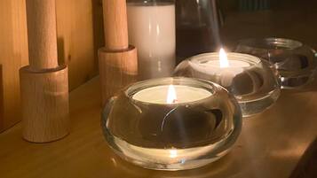 A wooden shelf with candles, a water bottle, and a vase of flowers.