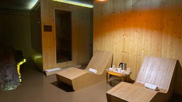 Relax in a serene sauna with two reclining chairs and a convenient table for refreshments.