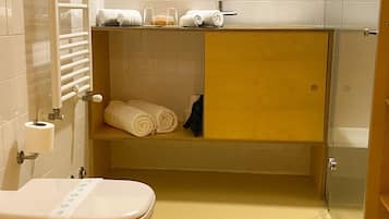 Un baño con inodoro, lavamanos y zona de ducha.