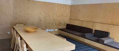 A modern interior with a wooden dining table, chairs, and a built-in sofa area.