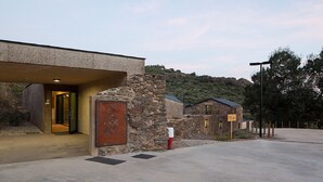 A modern building with a stone facade, a large entrance, and a parking area.
