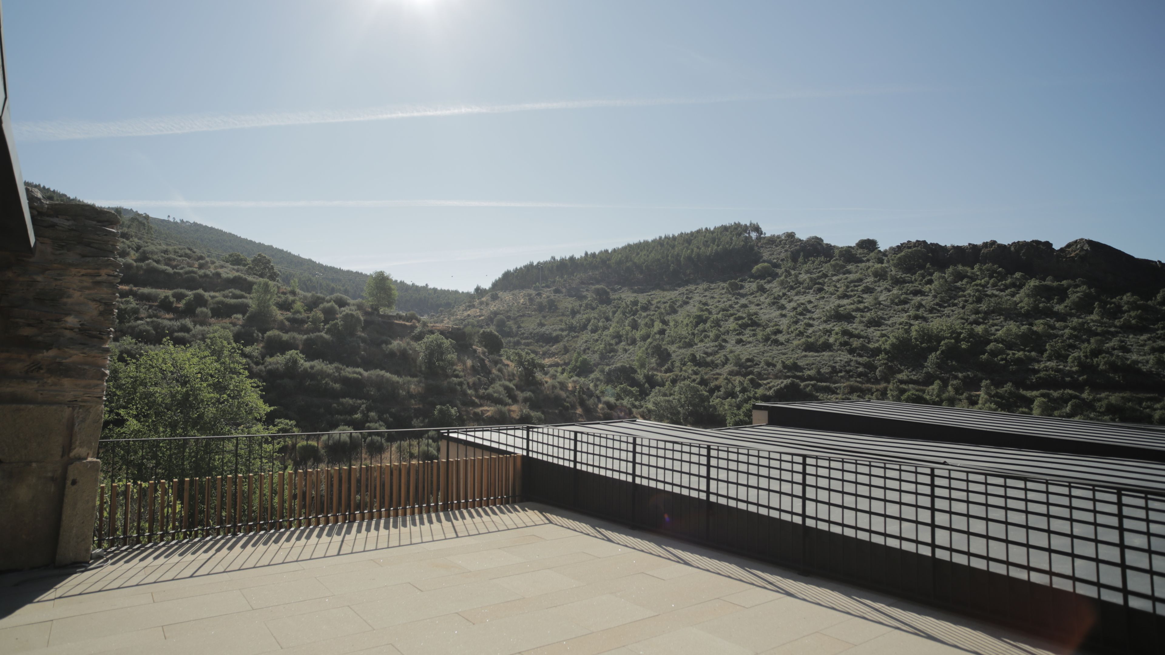 A terrace with a view of a hilly landscape.