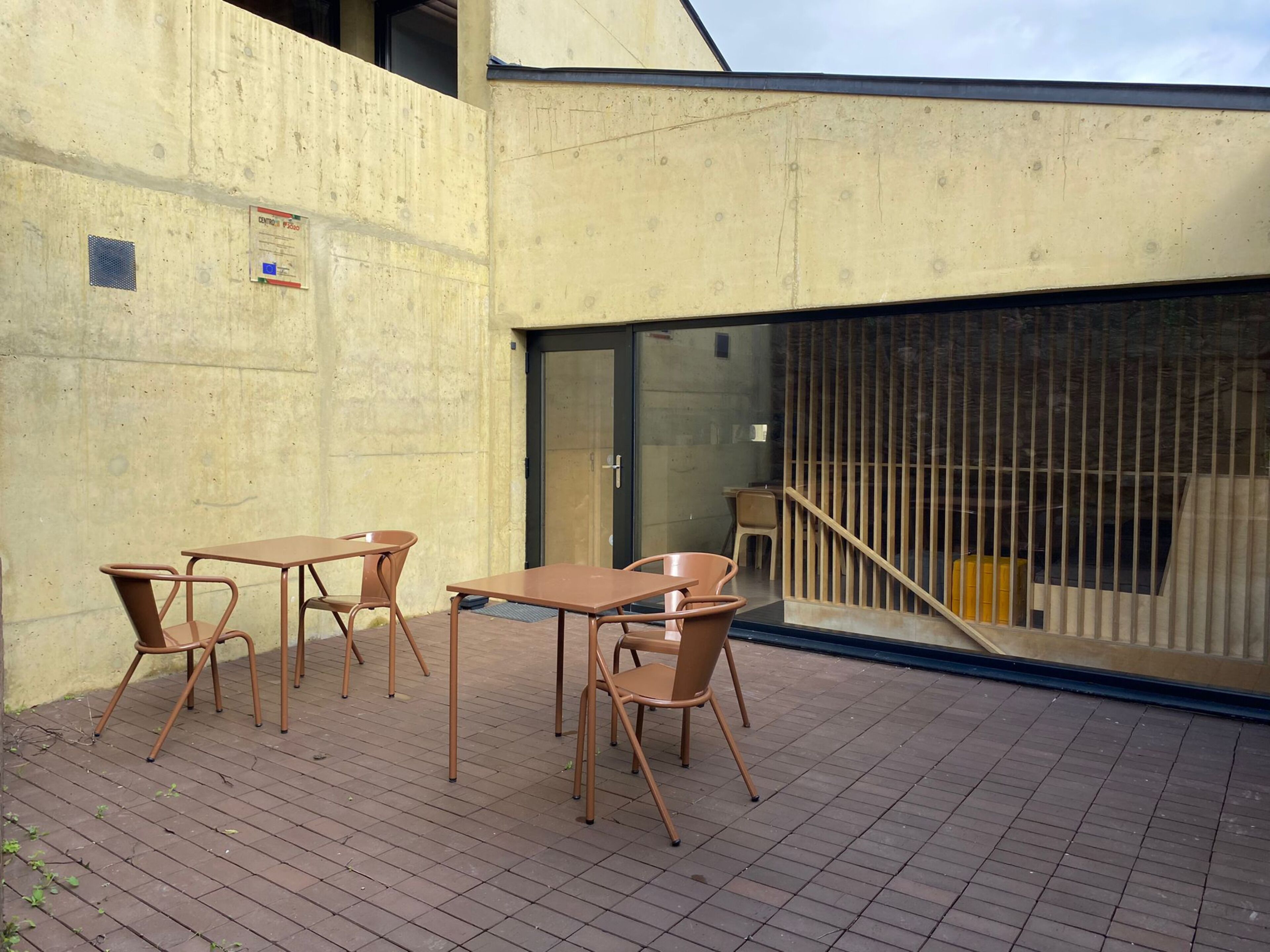 An outdoor patio area with a concrete wall, a glass door, and a metal railing.