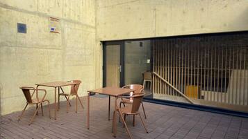 An outdoor patio area with a concrete wall, a glass door, and a metal railing.