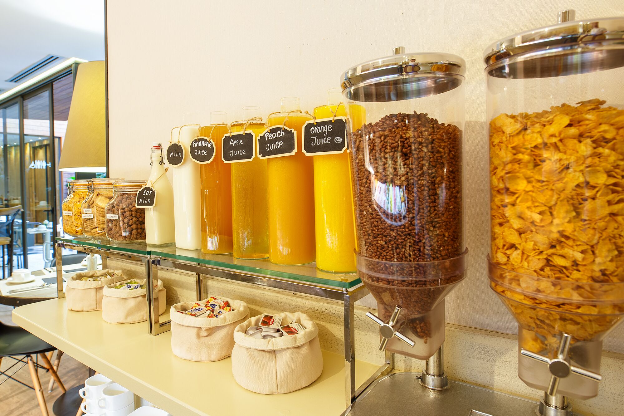 A buffet with various food and drink options, including jars of milk, juice, and cereal.