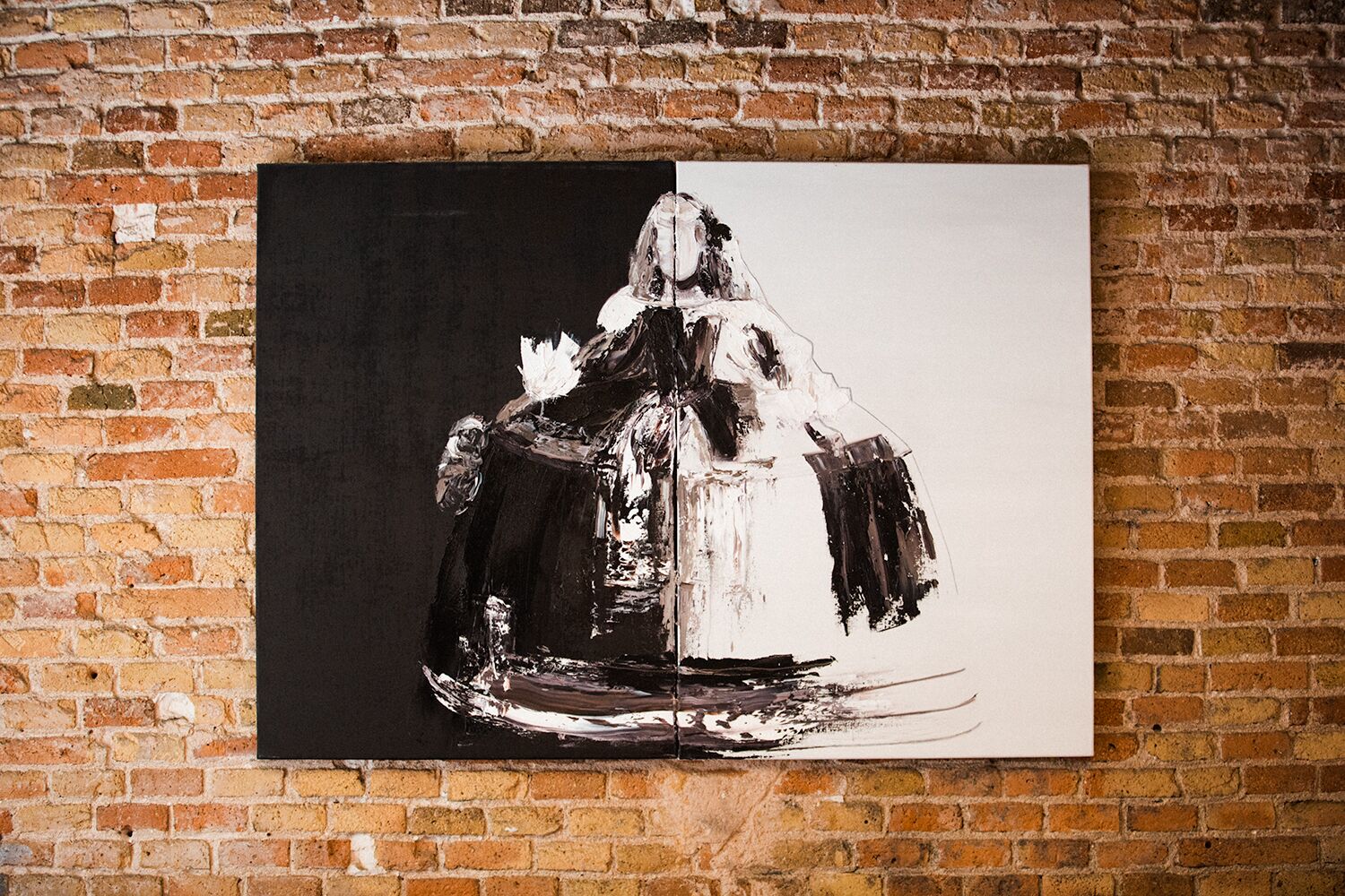 A painting of a figure in a white dress on a black background, mounted on a brick wall.