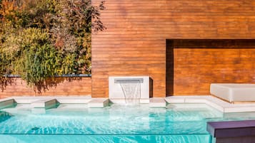 Una piscina al aire libre, sillones reclinables de piscina