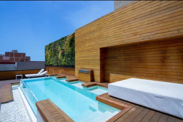 Una piscina al aire libre, sillones reclinables de piscina