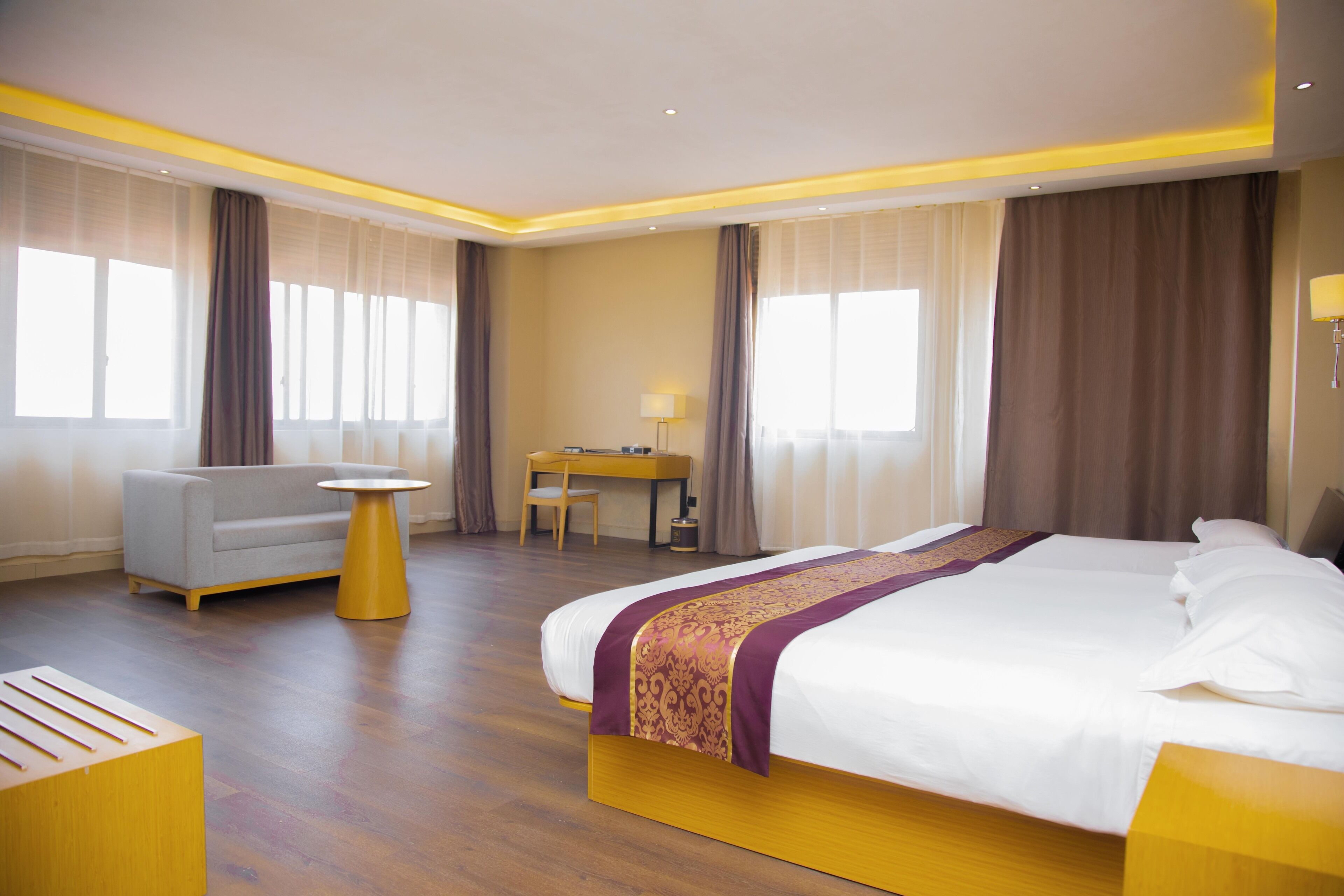 A hotel room with a large bed, a desk, a chair, and a sofa.