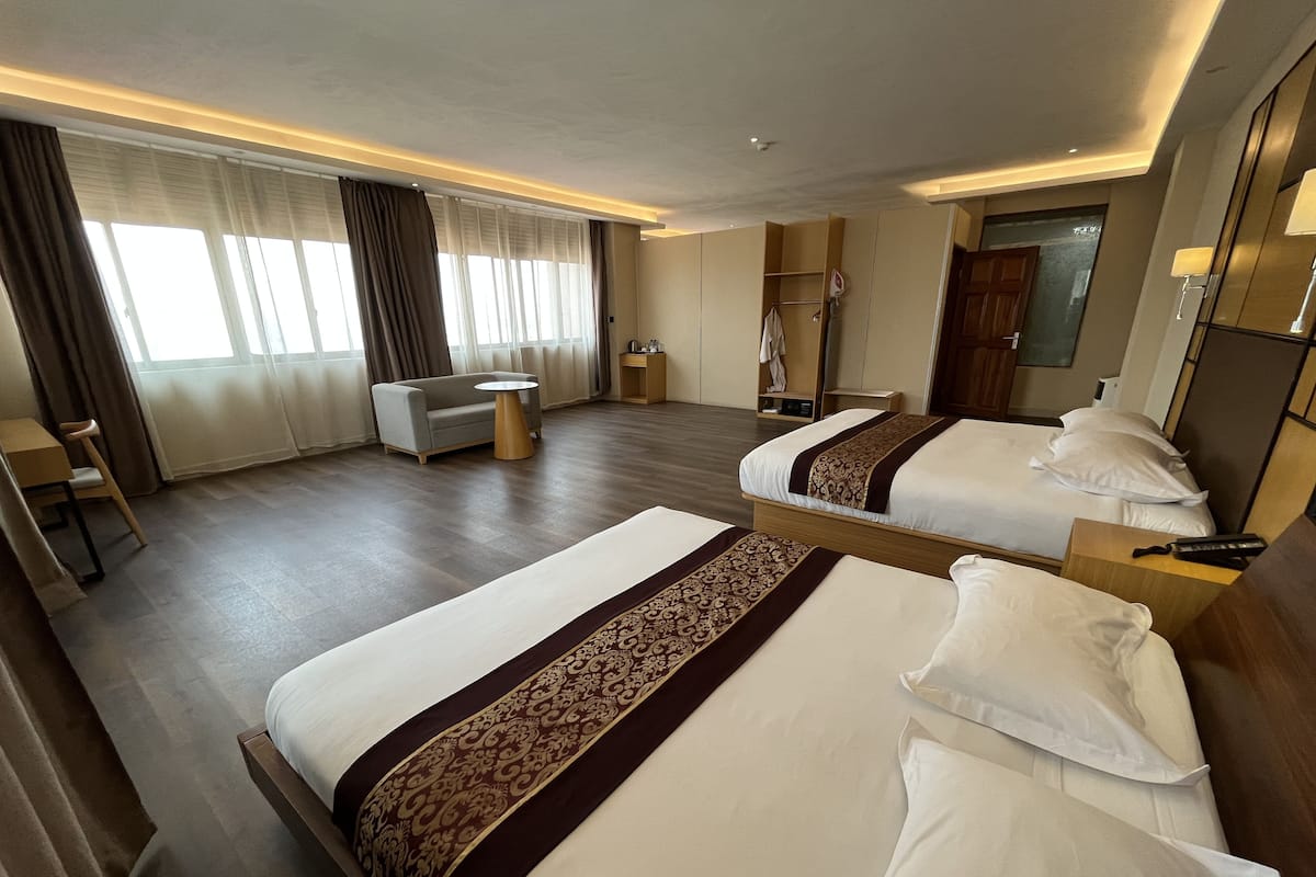 Una habitación de hotel con dos camas, un sofá, una mesita redonda y un armario.