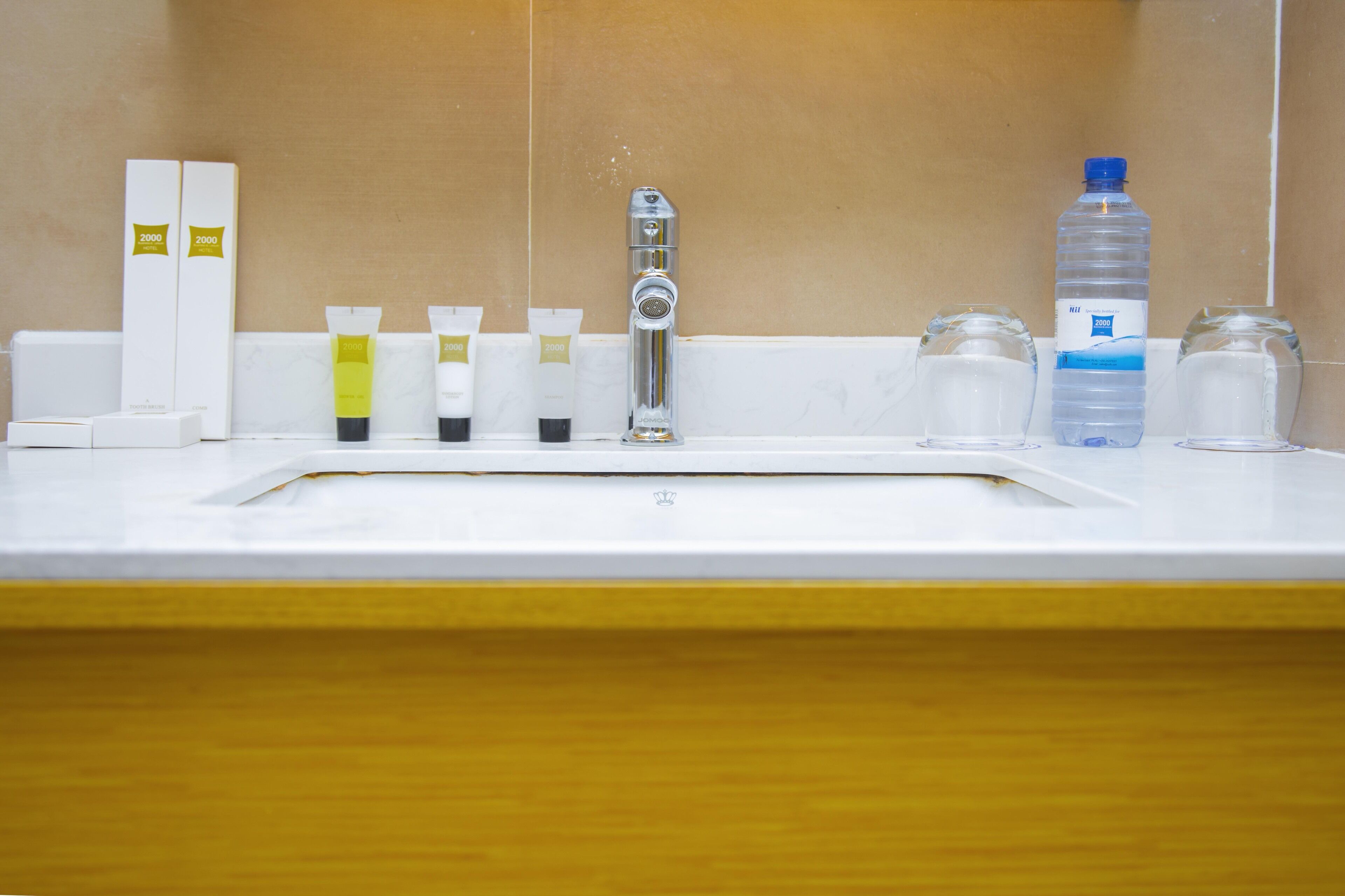 Un lavabo de salle de bain avec des articles de toilette, un robinet et une bouteille d’eau.