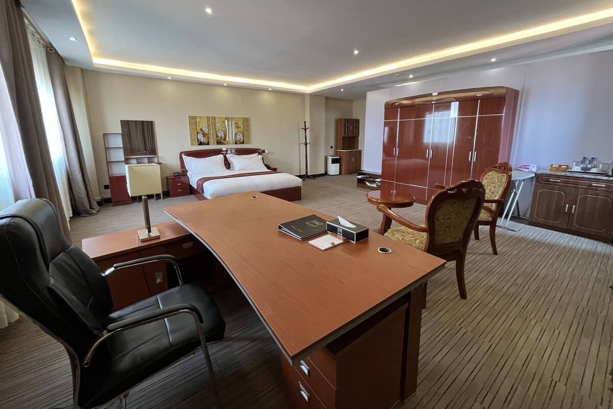 Una habitación de hotel con cama, escritorio, sillas y armario.