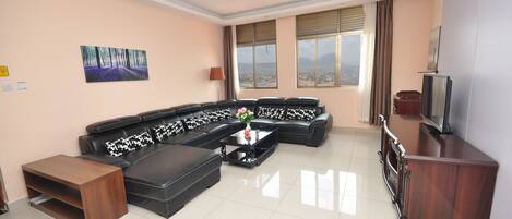 A modern living room with a sectional sofa, a coffee table, a TV stand, and a painting on the wall.