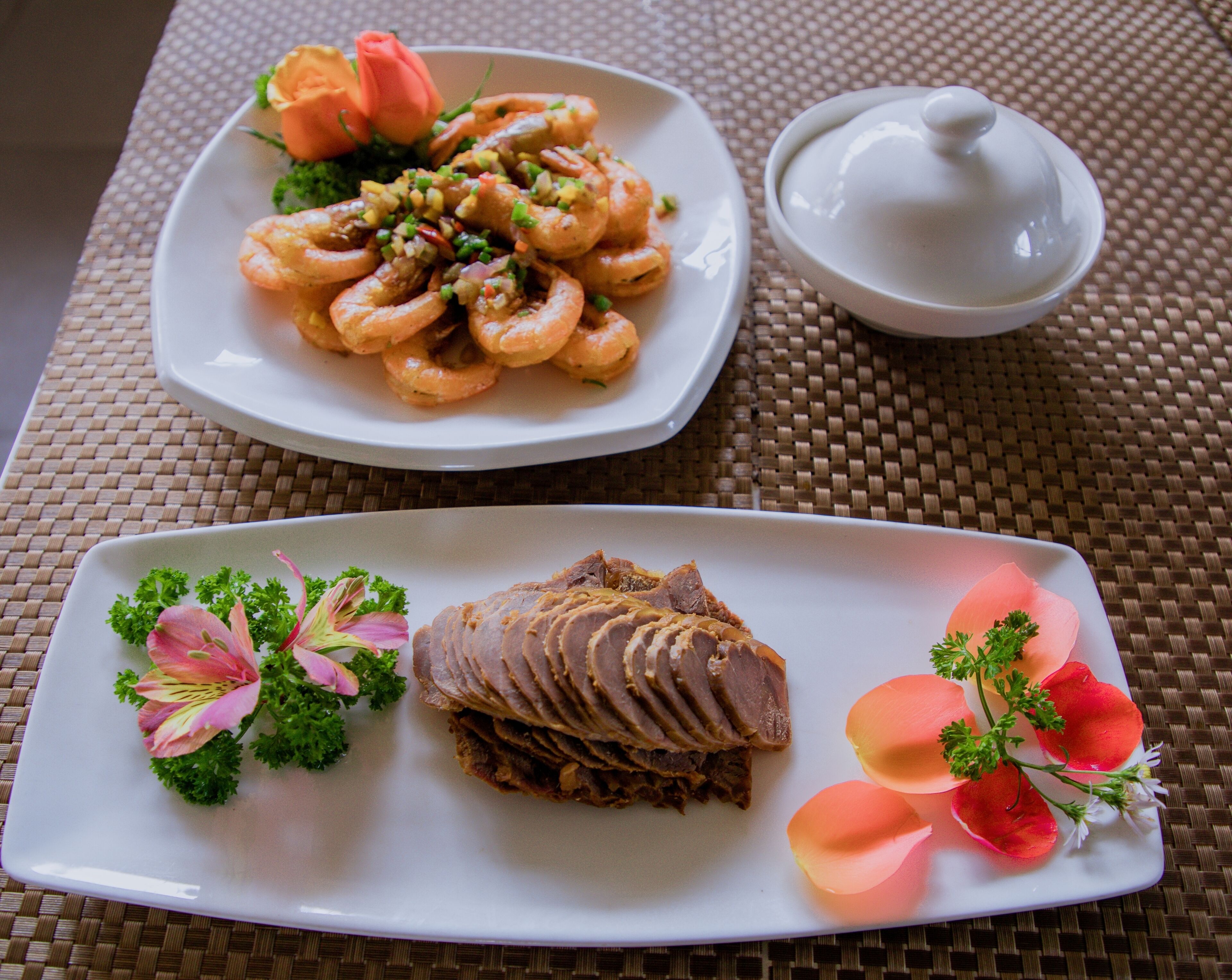 Two plates of food on a table with a woven placemat.