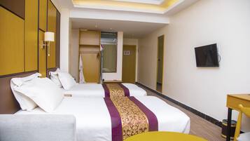 A hotel room with two beds, a desk, a chair, a TV, and a bathroom visible through an open door.