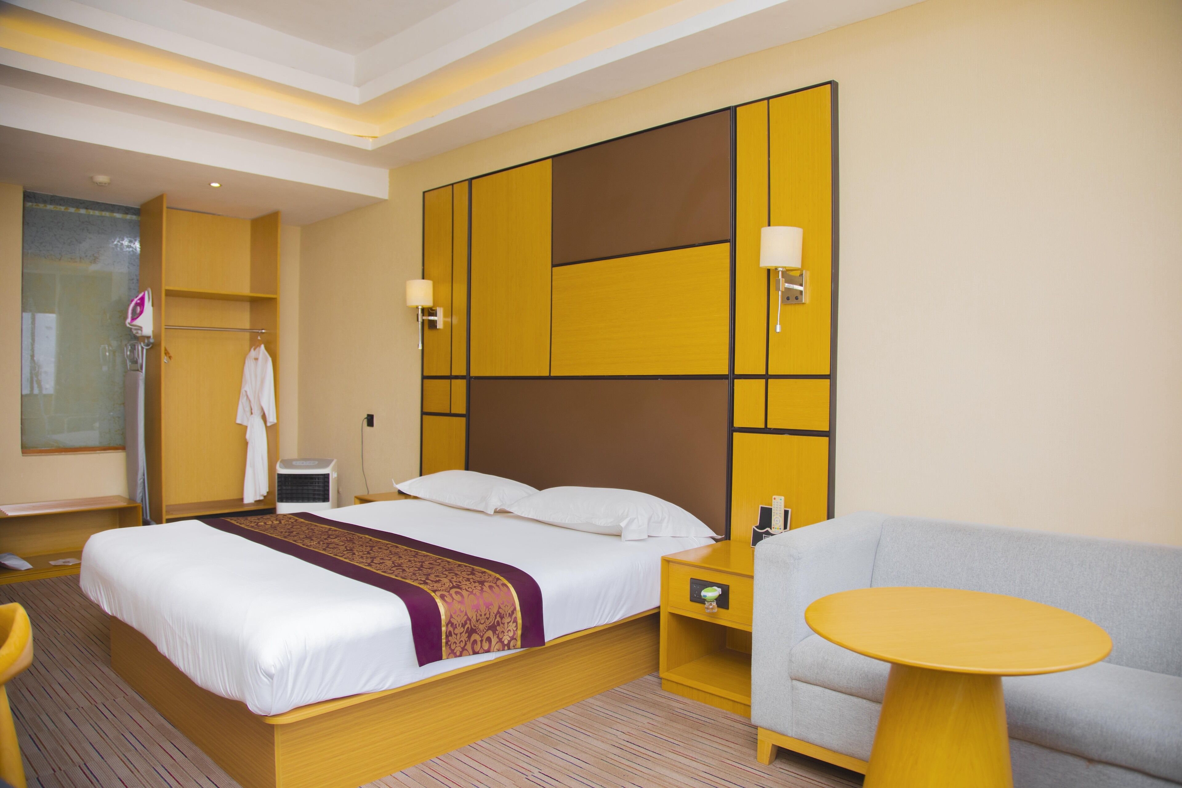 A hotel room with a bed, bedside table, and a sofa.