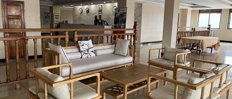 A spacious lobby with wooden furniture, a reception desk, and a view of the outside.