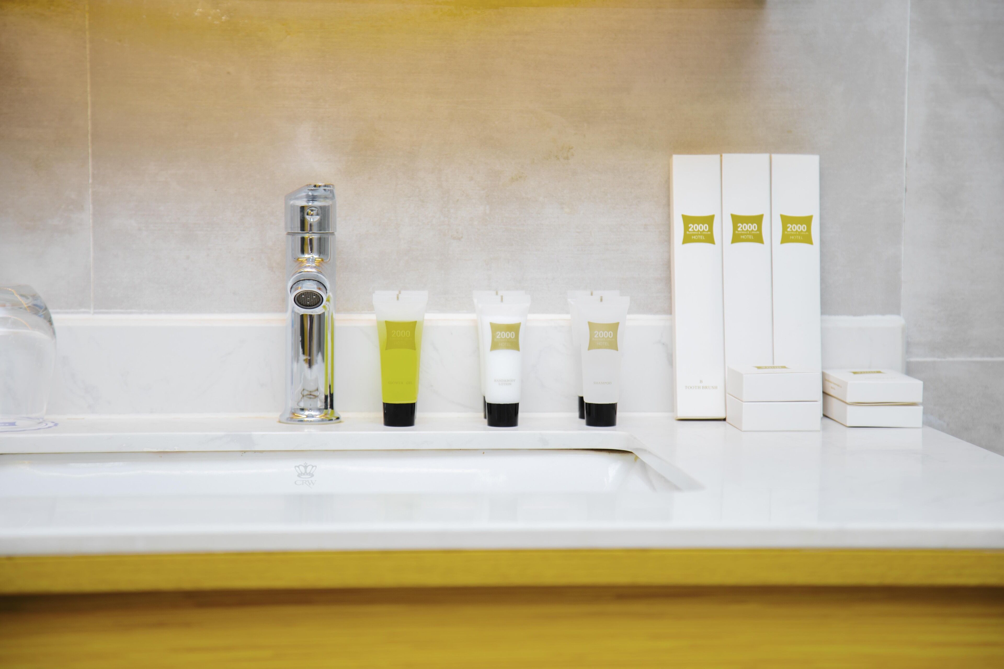 Une salle de bain avec un lavabo blanc, un robinet chromé et trois articles de toilette alignés.