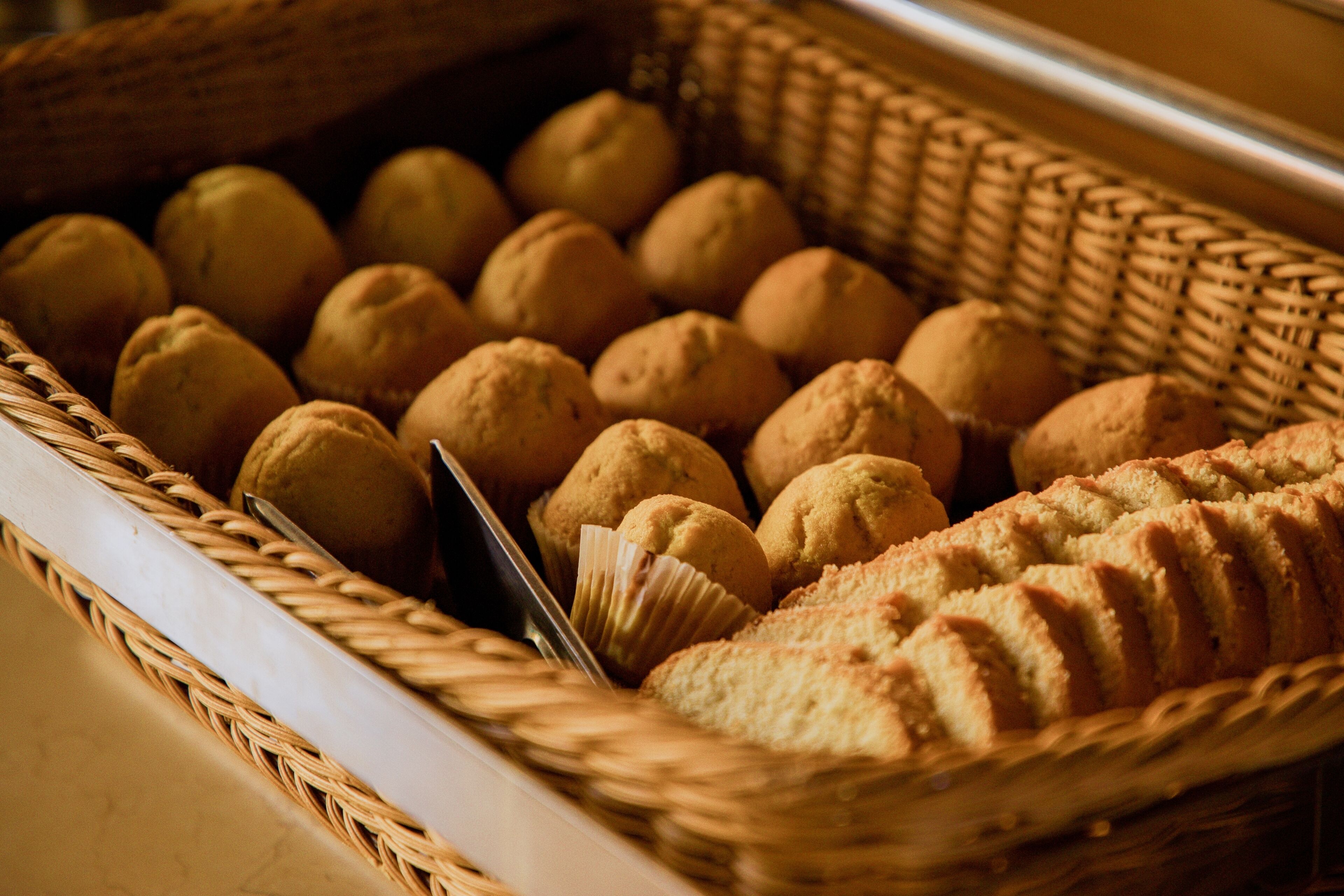 A wicker basket filled with round pastries and a loaf of bread.