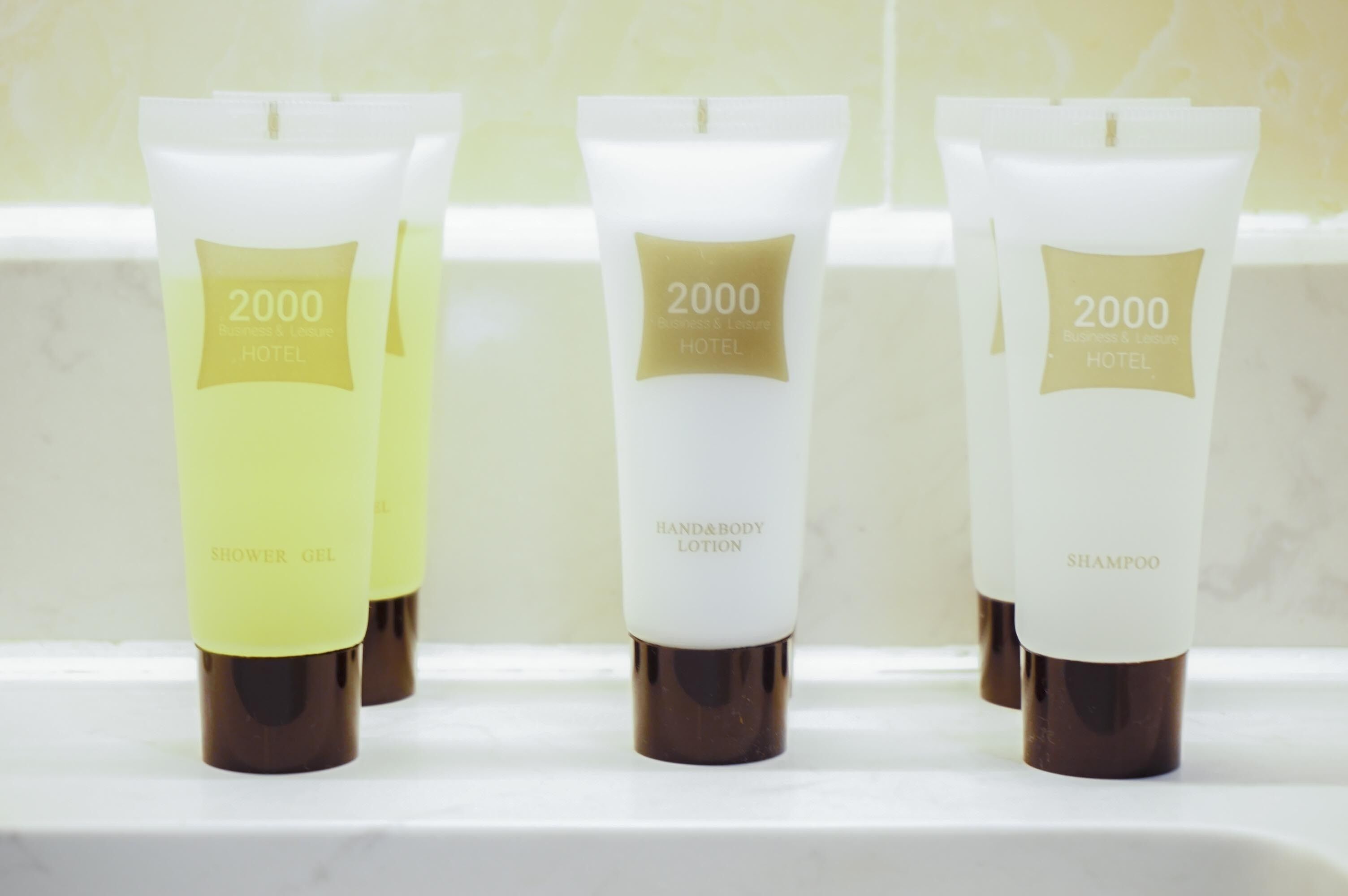 Three toiletry bottles labeled '2000 Hotel' on a white shelf.